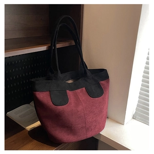 Close-up of minimalist dark red suede tote bag with black trim detailing in natural light