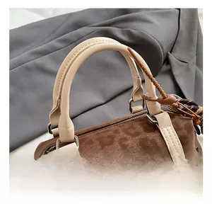 Detailed embroidery of a cartoon bear on a brown suede Boston handbag with zipper