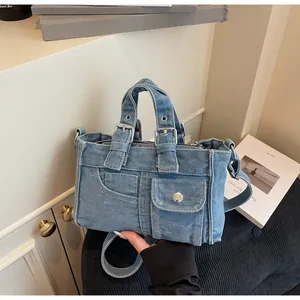 Detail view of the multi-pocket blue denim tote bag with adjustable shoulder strap