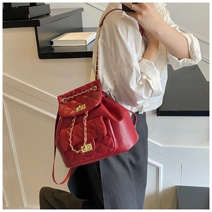 Detailed view of red quilted leather backpack with gold chain straps and twist lock