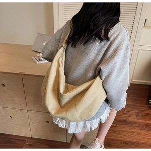 Detail of beige canvas crescent bag with vertical stitching and wide shoulder strap