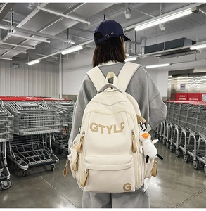 Off-white canvas student backpack featuring khaki GTYLF embroidery and a plush duck charm