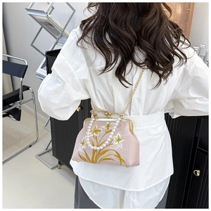 Detailed embroidery of white flowers and gold leaves on a pink satin cheongsam handbag