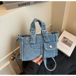 Detail view of denim handbag with pocket design and adjustable shoulder strap