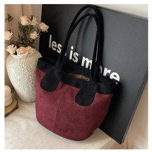 Detail view of burgundy and black suede tote bag with elegant long double handles