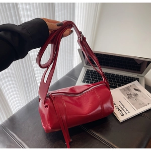 Detail of red glossy leather cylinder Boston bag with silver hardware and adjustable strap