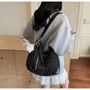 Close-up of black tweed shoulder bag with gold silk texture and plush bunny charm accessory
