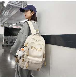 Detail of cream multi-pocket backpack with GTYLF embroidery and cute duck plush charm