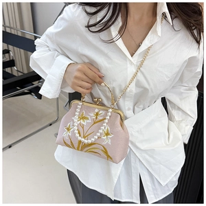 Detailed close-up of pink silk embroidery bag with pearl handle and golden frame
