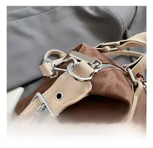 Close-up of premium silver metal buckle and brown leather stitching on a stylish bag