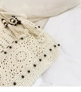 Detail of crochet tote bag featuring intricate hollow patterns and brown wooden beads