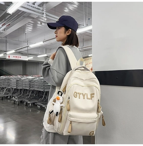 Detail of a large beige backpack with GTYLF letter embroidery and a small duck keychain