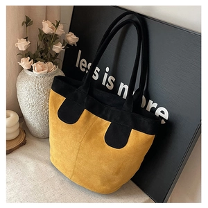 Detail of minimalist two-tone tote bag featuring yellow suede texture and black trim