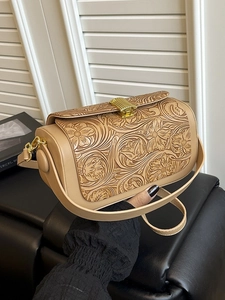 Retro khaki crossbody bag with floral embossing and gold metal lock held by hand