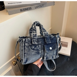 Detail of vintage denim tote bag showing pockets, metal buckles, and distressed blue texture