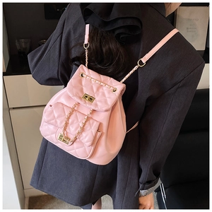 Detailed view of pale pink quilted leather mini backpack with gold chain straps on model
