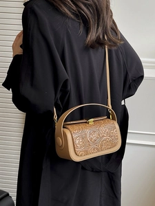 Vintage brown cylindrical handbag with floral embossing and adjustable shoulder strap