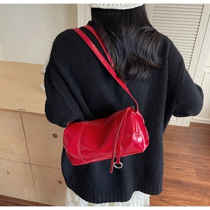 Detail of red cylindrical pillow bag in glossy finish with metal ring zipper puller