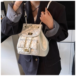 Detailed close-up of white quilted mini backpack with gold chain straps and twist-lock buckle