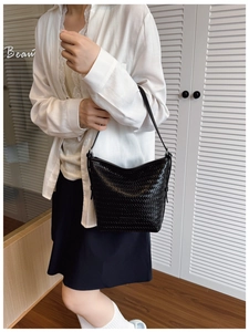 Close-up of black woven leather bucket bag with fine cross-grid texture and slim strap