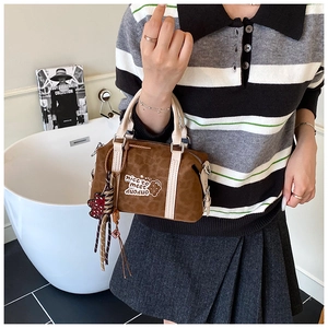 Detail einer braunen Boston-Tasche mit Leopardenmuster, Bärenanhänger und Ledergriffen