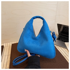Detail of royal blue suede shoulder bag showing matte texture and knotted strap design
