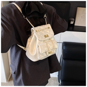 Close-up of white quilted leather texture with gold-tone metal twist lock on a bucket bag