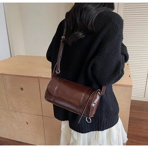 Detail of dark brown boston bag with glossy finish and adjustable silver hardware