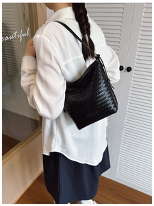 Model view showing the back profile of a black woven leather shoulder bucket bag
