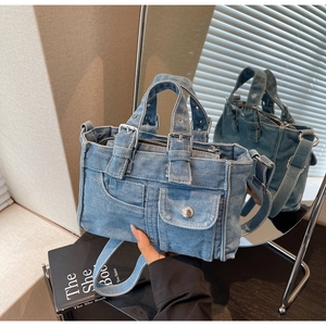 Detail view of denim tote bag with metal buckles on a book with a mirror reflection