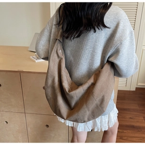 Brown slouchy dumpling crossbody bag shown on model in a cozy lifestyle setting