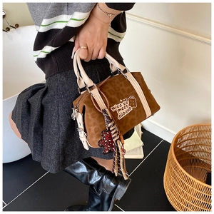 Close-up of brown suede Boston bag with leopard print and cute bear pendant detail