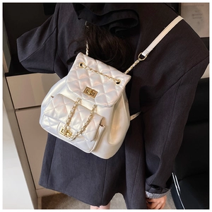 Detailed view of white quilted pearl leather backpack with golden chain strap on model