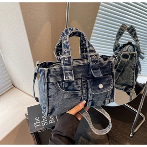 Detailed macro view of vintage blue denim handbag with metallic buckles and leather pullers