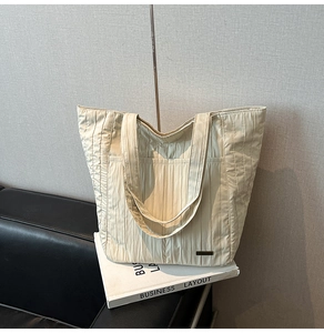 Detail der gesteppten beigen Shopper-Tasche mit Faltenstruktur und edlem Metall-Logo