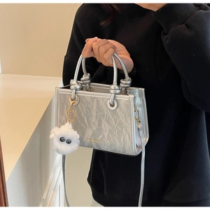 Detail of silver pleated mini bucket bag with fashion logo and plush monster charm