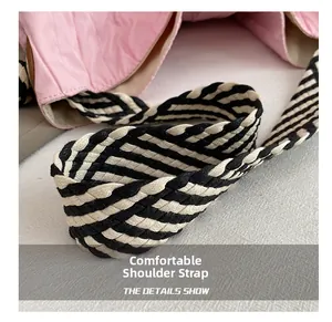 Détail de la bandoulière tissée rayée noir et blanc sur un sac en toile rose élégant