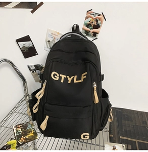 Close-up of black school backpack with cream GTYLF logo and multiple zipper pockets