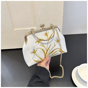 Detail of vintage white embroidery bag with floral pattern and classic metal frame clasp