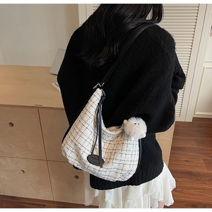 Large tweed tote bag with black straps and plush charm shown on a shoulder