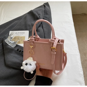 Close-up of pink leather bucket bag with gold embossing and plush monster charm detail