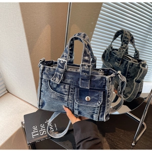 Detail view of washed blue denim tote bag with metal rivets and utilitarian pockets
