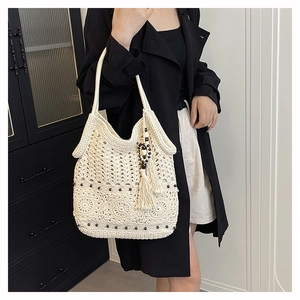 Detailed close-up of ivory crochet shoulder bag with hollow knit patterns and floral accents