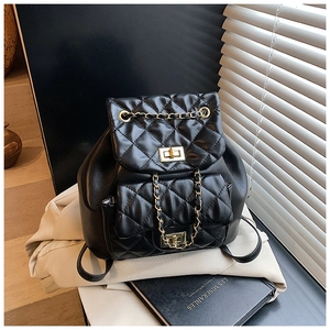 Detail of black quilted leather backpack showing golden twist lock and chain strap