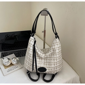 Close-up of white tweed large tote bag with black straps in a cozy lifestyle setting