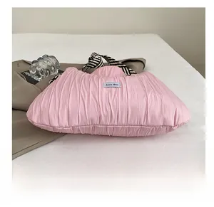 Détail du sac cabas plissé rose avec poignée rayée et étiquette de marque bleue