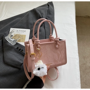 Detail of pink faux leather bucket bag with marble texture and furry charm accessory