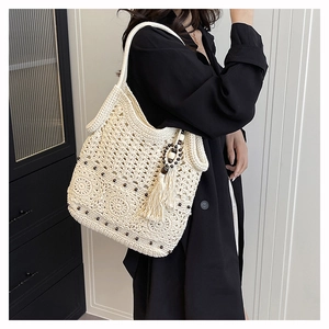 Detailed close-up of cream crochet tote bag featuring dark dots and fringe tassel decor