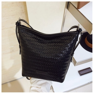 Detail of black woven texture on bucket bag with rectangular embossed brand logo