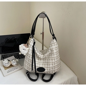 Detail of tweed checkered tote bag with plush sheep charm and stylish office accessories